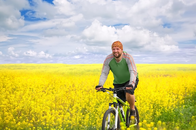 Mujer joven en bicicleta en campo de flores amarillas