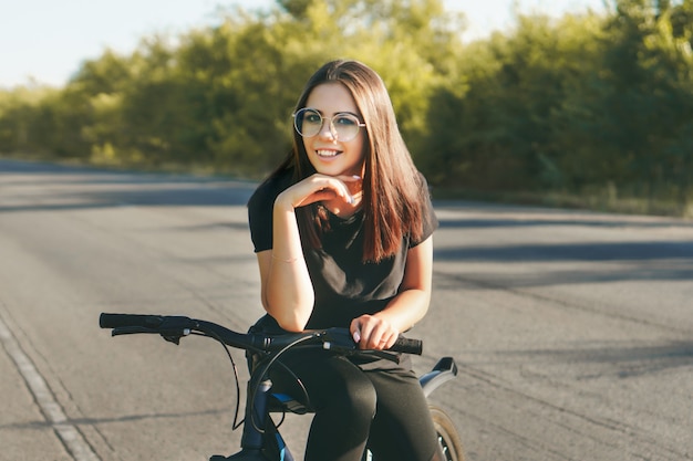 Mujer joven en bicicleta por la carretera