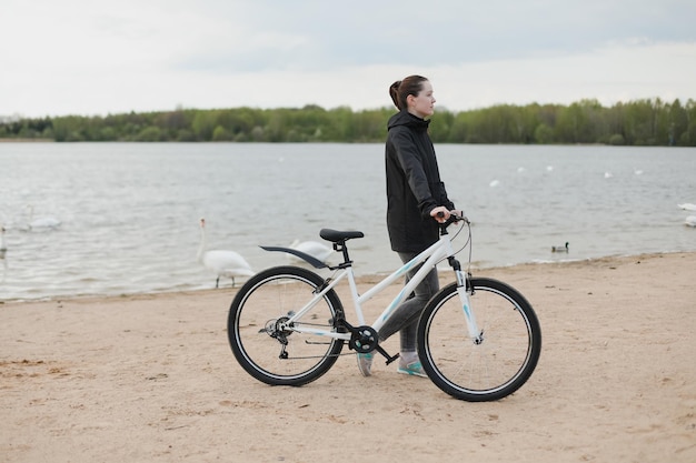 Una mujer joven con una bicicleta en el lago.