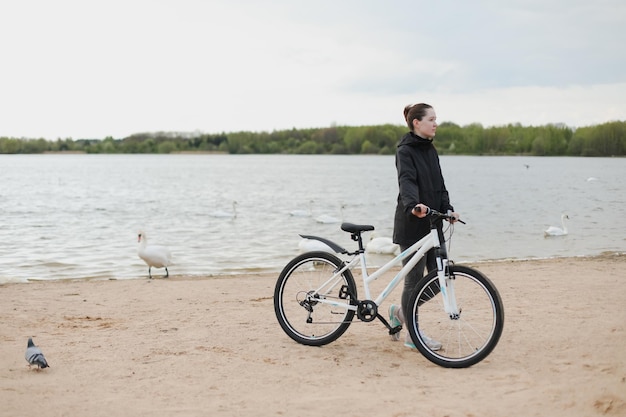 Una mujer joven con una bicicleta en el lago.