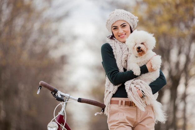 Mujer joven con una bicicleta y un lindo perro