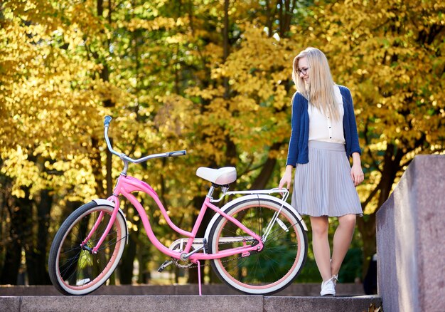 Mujer joven con una bicicleta rosa