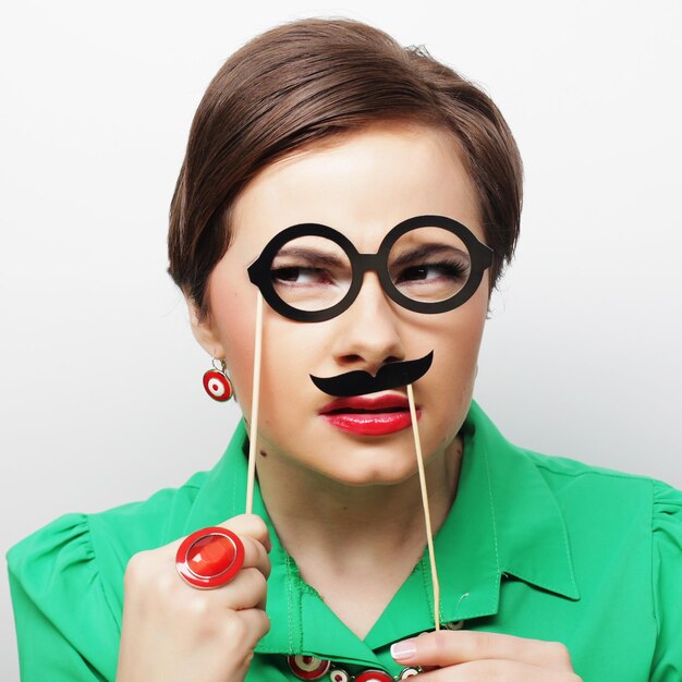 Foto mujer joven con bigote y gafas en un palo