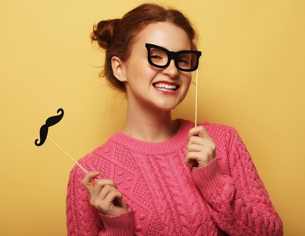 Mujer joven con bigotes falsos y gafas sobre centrico amarillo