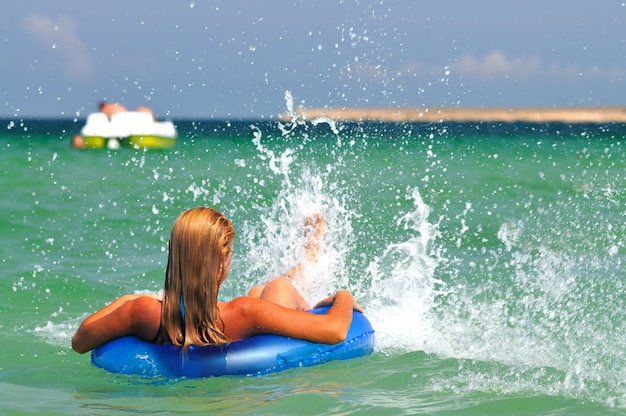 Mujer joven en bikini al revés en agua de mar en círculo de natación