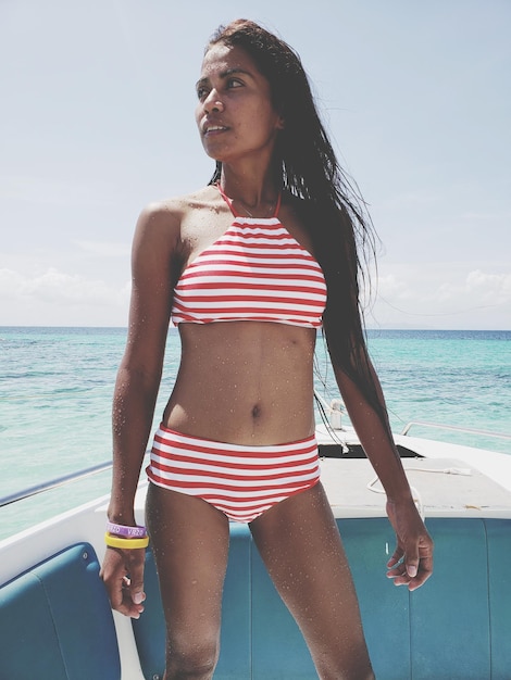 Mujer joven con bikini de pie en un barco en el mar durante un día soleado
