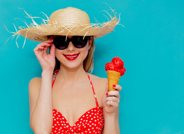 Mujer joven en bikini rojo y sombrero de paja con helado