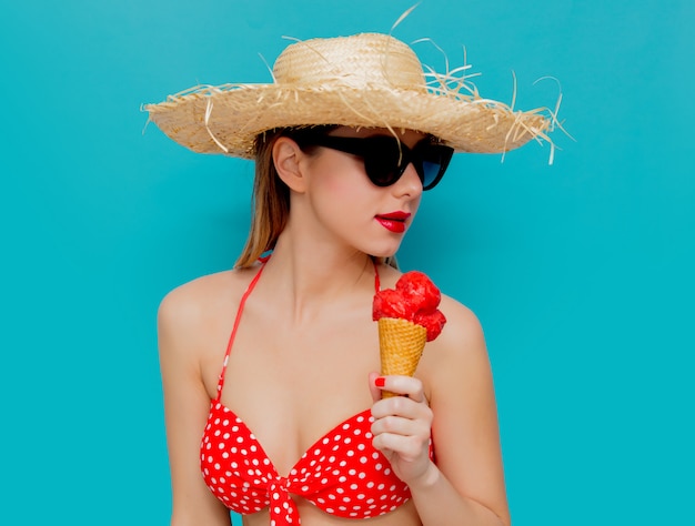 Mujer joven en bikini rojo y sombrero de paja con helado