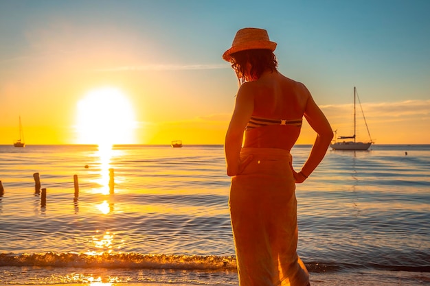 Una mujer joven en bikini con sombrero en una puesta de sol en Roatán Honduras