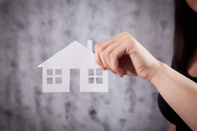 Una mujer joven de blanco tiene una casa.