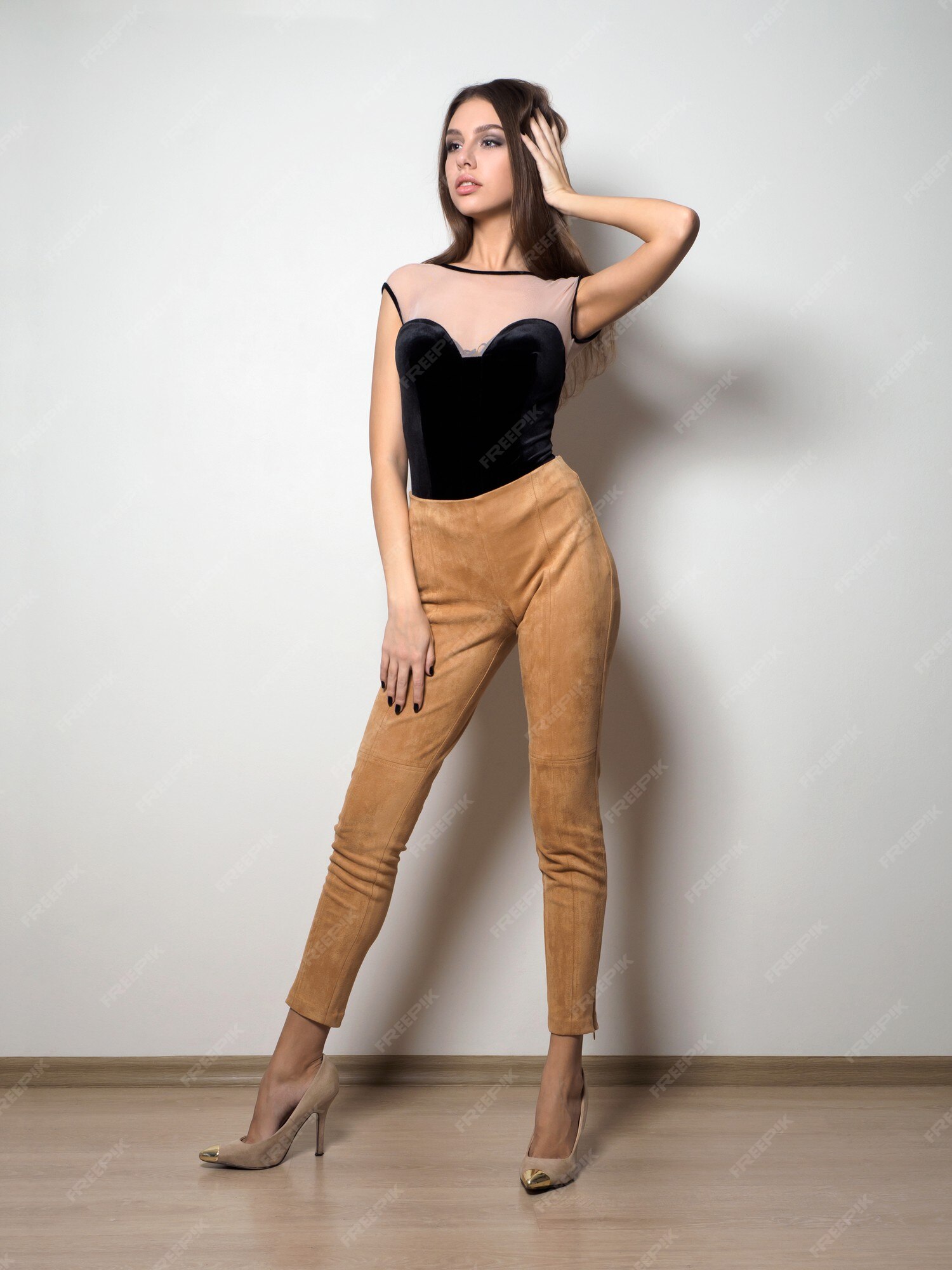 Mujer joven blusa y pantalón beige posando sobre blanca | Foto