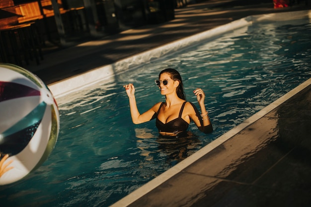 Mujer joven con bola en la piscina