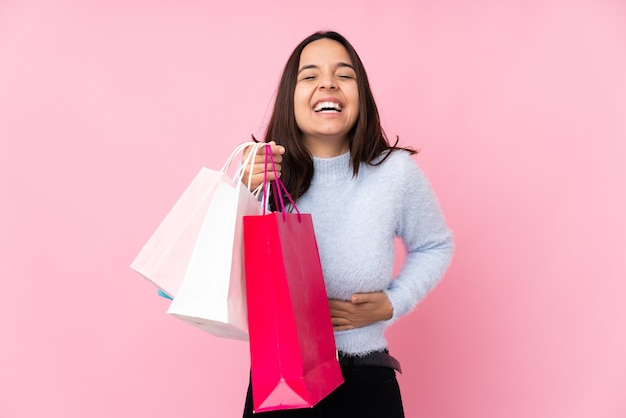 Foto mujer joven con bolsa de compras sobre pared rosa aislada sonriendo mucho