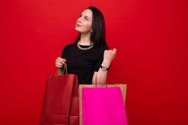 Una mujer joven con bolsas de colores sobre un fondo rojo.