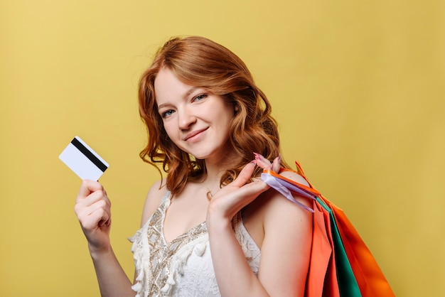 mujer joven con bolsas de compra y una tarjeta de crédito