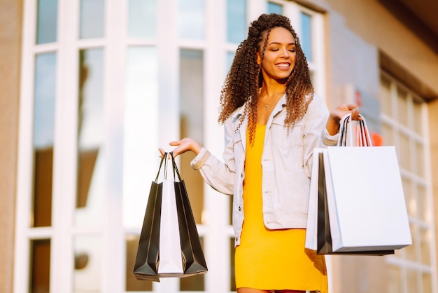 Mujer joven con bolsas de compras caminando por la calle Venta de compras y concepto de gente feliz