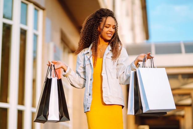 Mujer joven con bolsas de compras caminando por la calle Venta de compras y concepto de personas felices