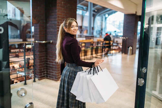 Mujer joven con bolsas de compras en el centro comercial.