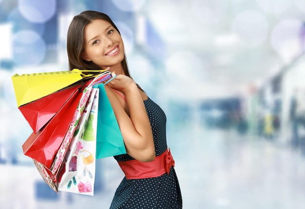 Mujer joven con bolsas de compras sobre fondo claro