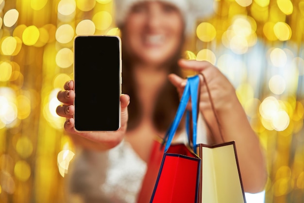 Mujer joven con bolsas de compras sobre fondo dorado con teléfono