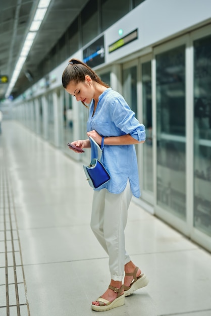 Mujer joven con bolso en la estación de metro.