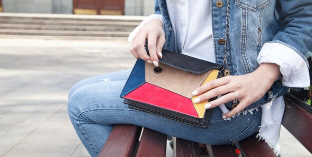 Mujer joven con bolso sentado en un banco.