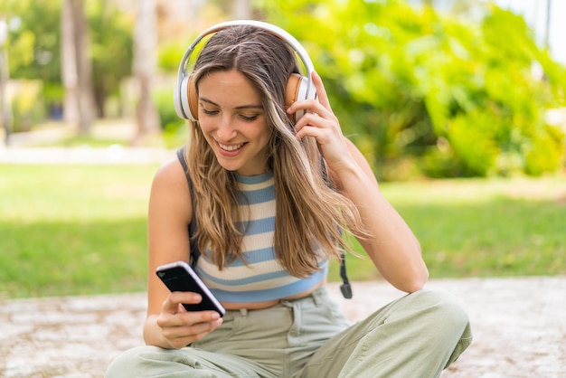 Mujer joven y bonita al aire libre usando teléfono móvil