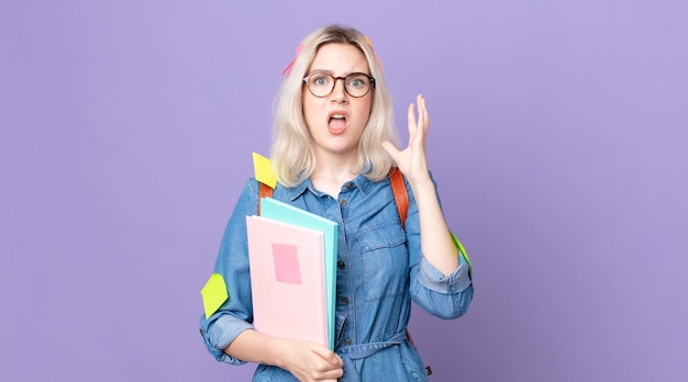 Mujer joven y bonita albina gritando con las manos en el aire. concepto de estudiante