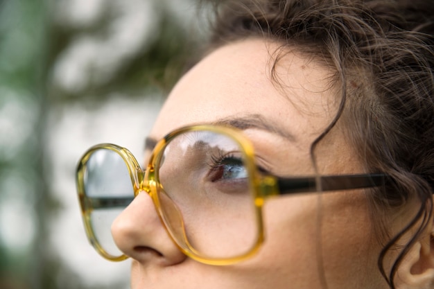 Mujer joven y bonita con anteojos al aire libre en el bosque