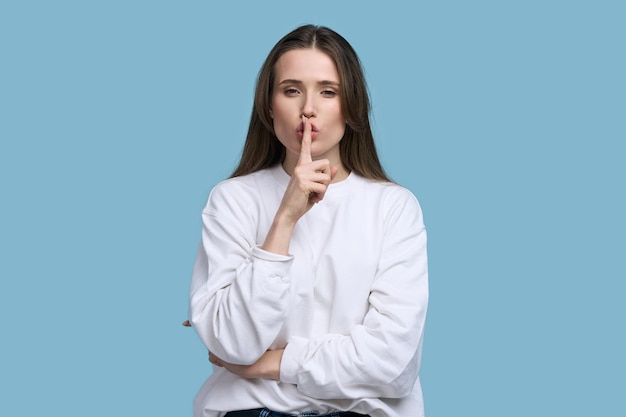 Mujer joven y bonita caucásica poniendo su dedo índice en sus labios mostrando el signo de silencio