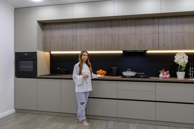 Mujer joven y bonita en la cocina lujosa gris moderna