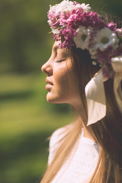 Foto mujer joven y bonita con flores en un pelo en un día soleado de primavera