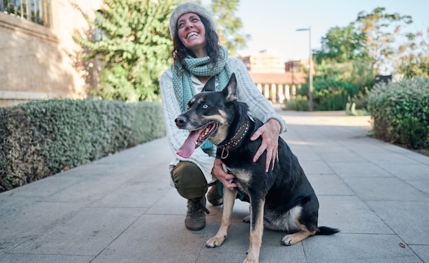 Una mujer joven y bonita con gorra blanca abraza y besa a su perro con un ojo de cada color.