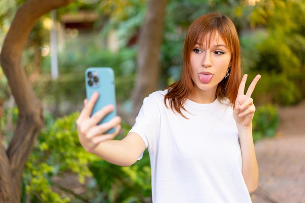 Mujer joven bonita pelirroja al aire libre mediante teléfono móvil