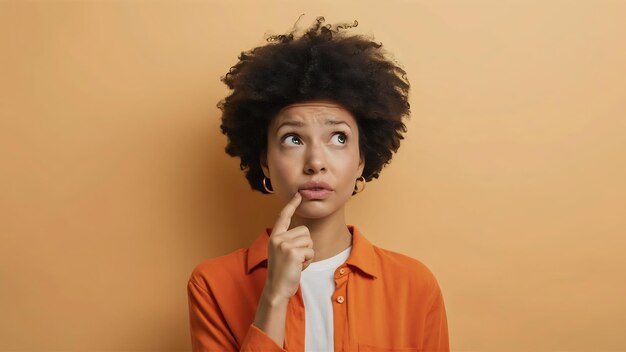 Mujer joven y bonita pensando en el problema emoción confusa aislada con camisa naranja hipste