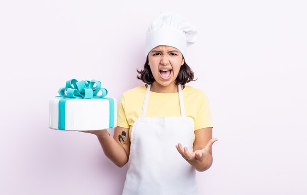 Mujer joven y bonita que parece enojada, molesta y frustrada. chef cocinando un pastel