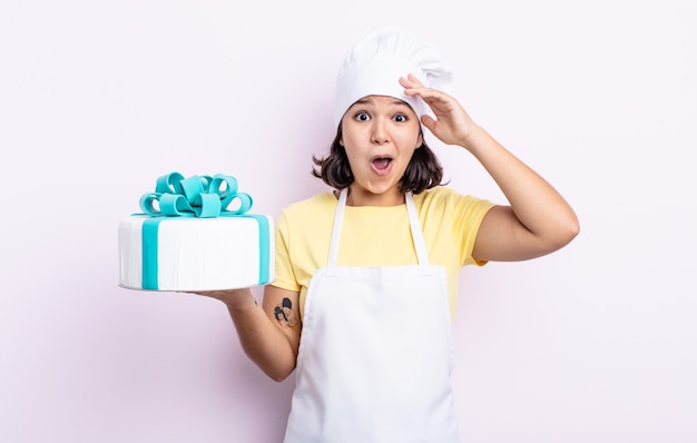 Mujer joven y bonita que parece feliz, asombrada y sorprendida. chef cocinando un pastel