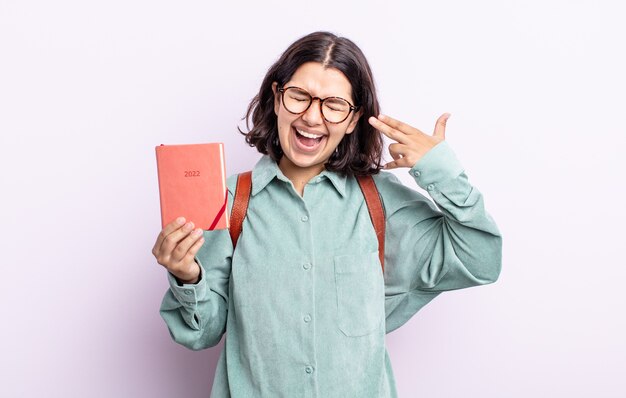 Mujer joven y bonita que parece infeliz y estresada, gesto de suicidio haciendo signo de pistola. Concepto de agenda 2022