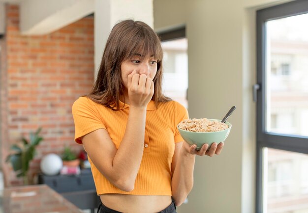 Foto mujer joven y bonita que se siente asustada, preocupada o enojada y mirando hacia el concepto de tazón de desayuno lateral