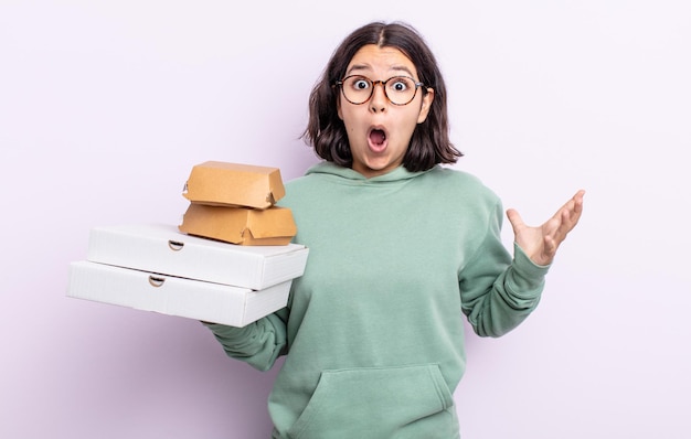 Mujer joven y bonita que se siente extremadamente conmocionada y sorprendida. concepto de comida rápida para llevar