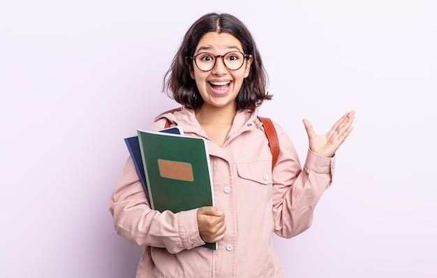 Mujer joven y bonita que se siente feliz y asombrada por algo increíble. estudiante con concepto de libros