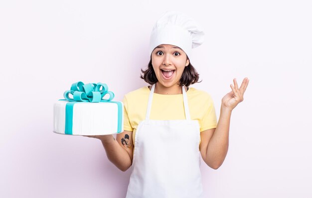 Mujer joven y bonita que se siente feliz, sorprendida al darse cuenta de una solución o idea. chef cocinando un pastel