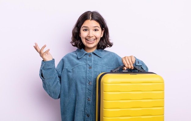 Mujer joven y bonita que se siente feliz, sorprendida al darse cuenta de una solución o idea. concepto de estuche de viaje