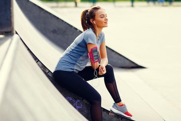 Mujer joven y bonita relajante durante el ejercicio en el parque en un día soleado