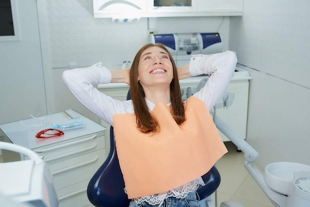 Una mujer joven y bonita se relajó en el sillón dental en el consultorio de un dentista