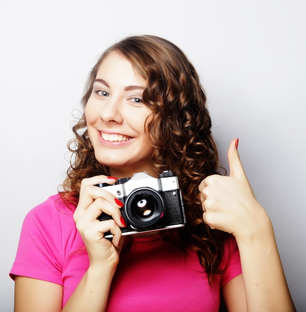 Foto mujer joven bonita sosteniendo cámara vintage sobre fondo gris