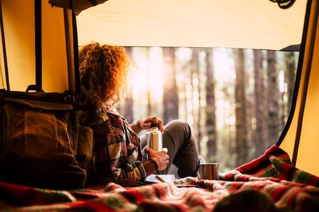 Mujer joven en el bosque con una carpa