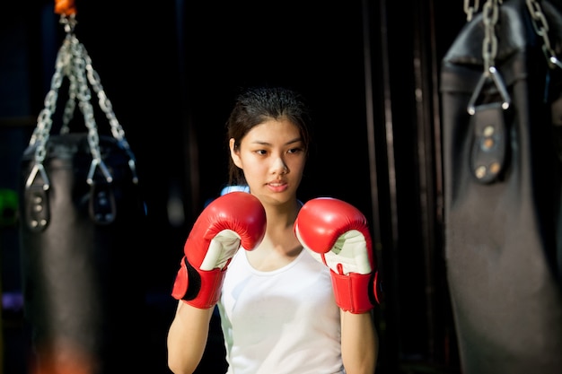 mujer joven boxeador en guantes de boxeo con saco de boxeo