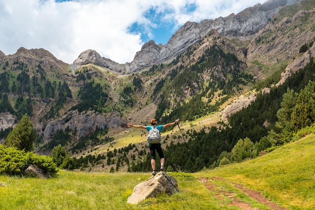 Una mujer joven con los brazos abiertos en la montaña en verano en el Pirineo Alto Gallego Huesca Aragón