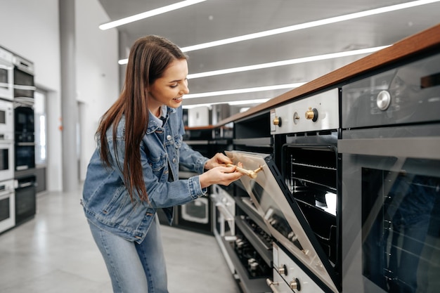 Mujer joven en busca de nuevo horno eléctrico en un centro comercial